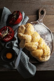 Photo of Homemade braided bread and ingredients on wooden table, flat lay. Cooking traditional Shabbat challah
