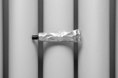 Photo of Tube of glue on grey paper rolls, top view