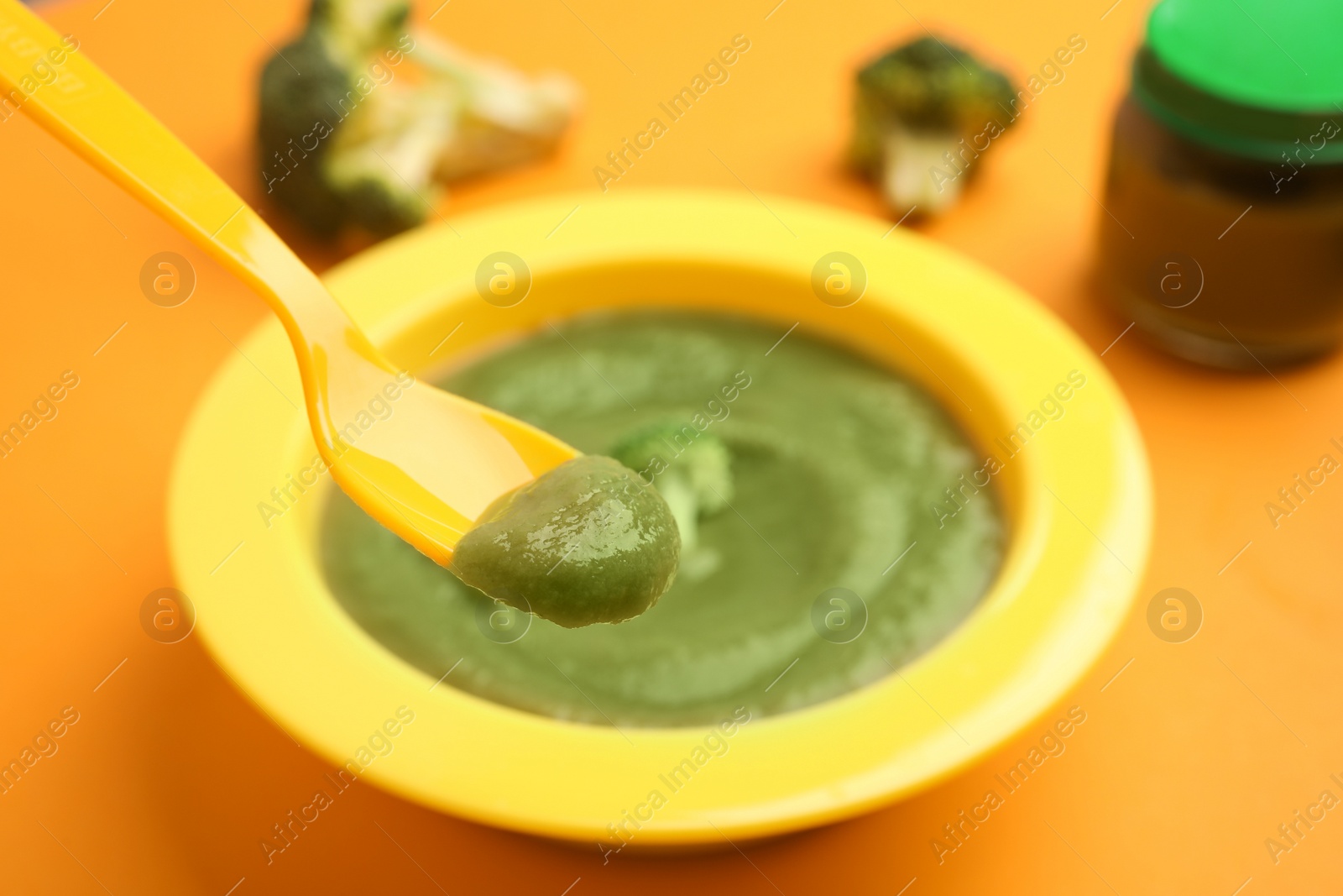 Photo of Healthy baby food and broccoli on orange background, closeup