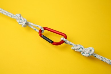 Photo of One metal carabiner with ropes on yellow background