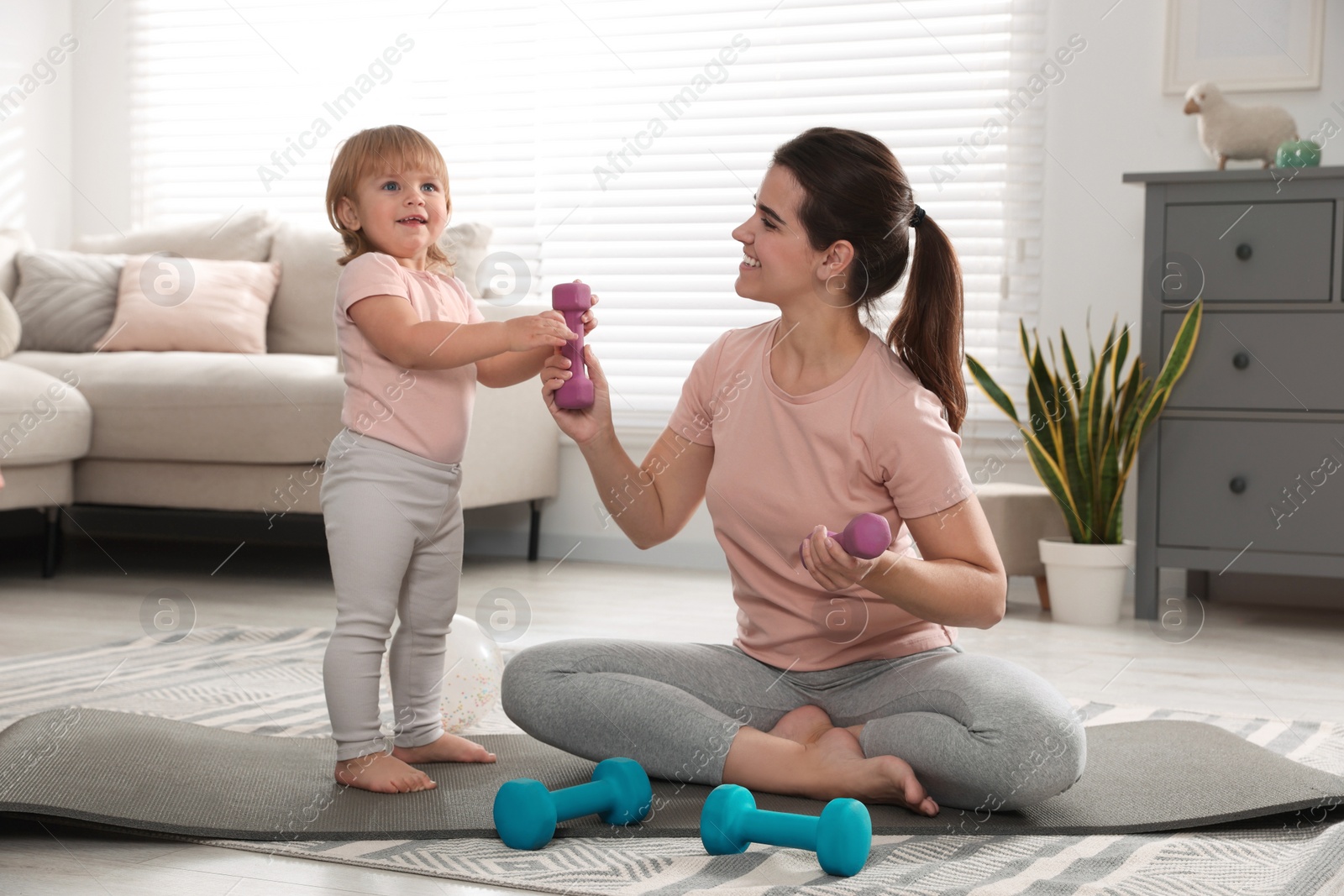 Photo of Mother and her daughter with dumbbells at home