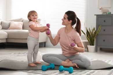 Photo of Mother and her daughter with dumbbells at home