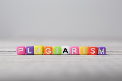 Photo of Colorful cubes with word Plagiarism on white wooden table