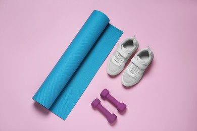 Photo of Exercise mat, dumbbells and shoes on pink background, flat lay