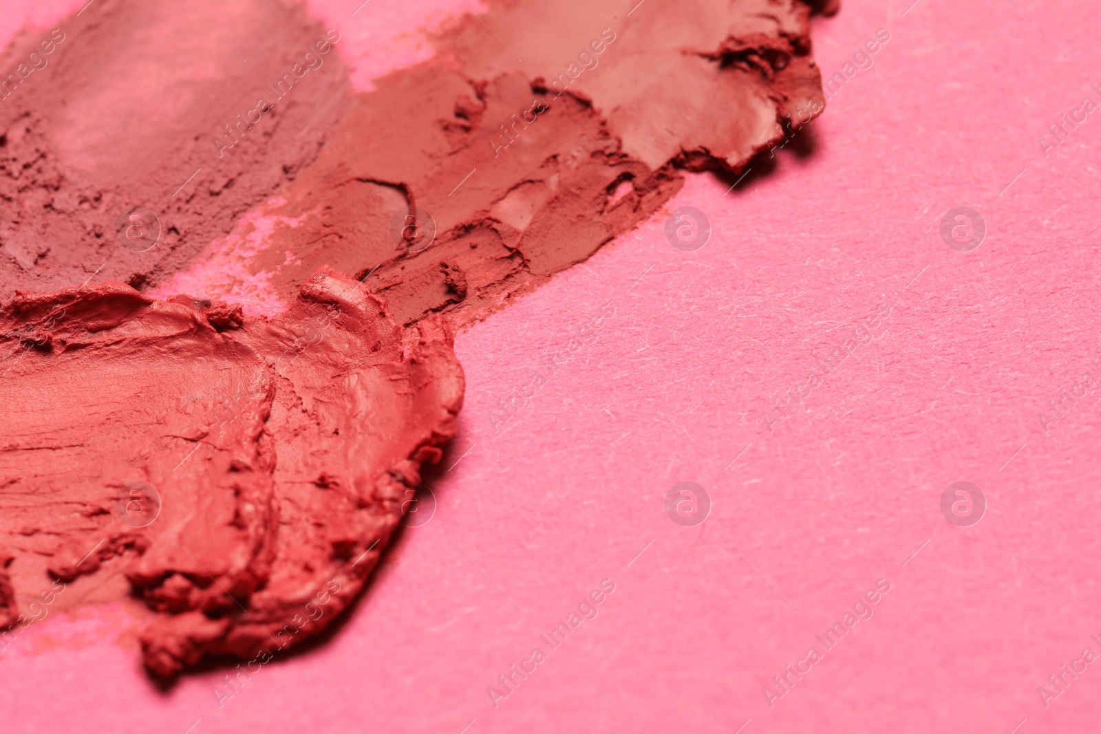 Photo of Smears of beautiful lipsticks on pink background, closeup. Space for text