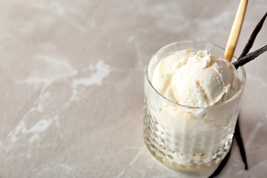 Photo of Glass with tasty vanilla ice cream on light background