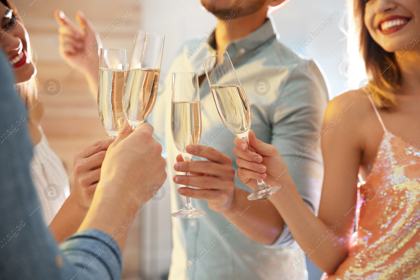 Photo of Friends clinking glasses with champagne at party indoors, closeup