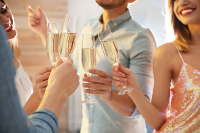 Friends clinking glasses with champagne at party indoors, closeup