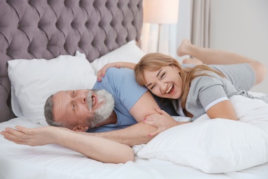 Photo of Mature couple having fun together on bed at home