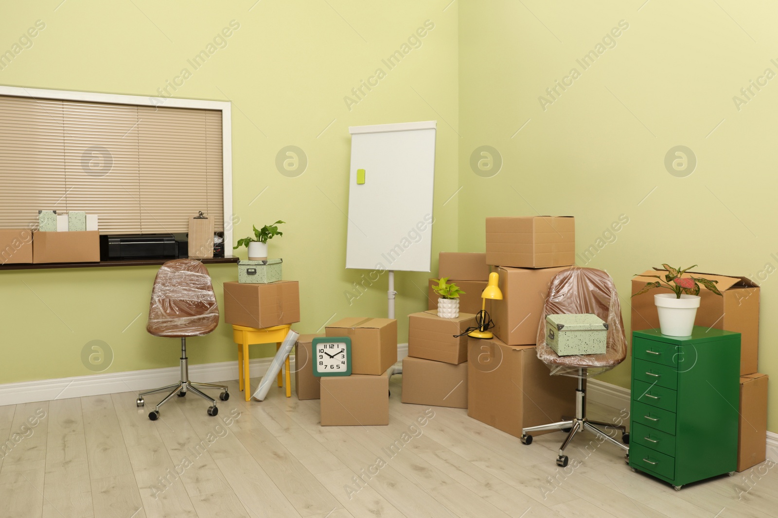 Photo of Cardboard boxes with packed stuff in new office. Moving day