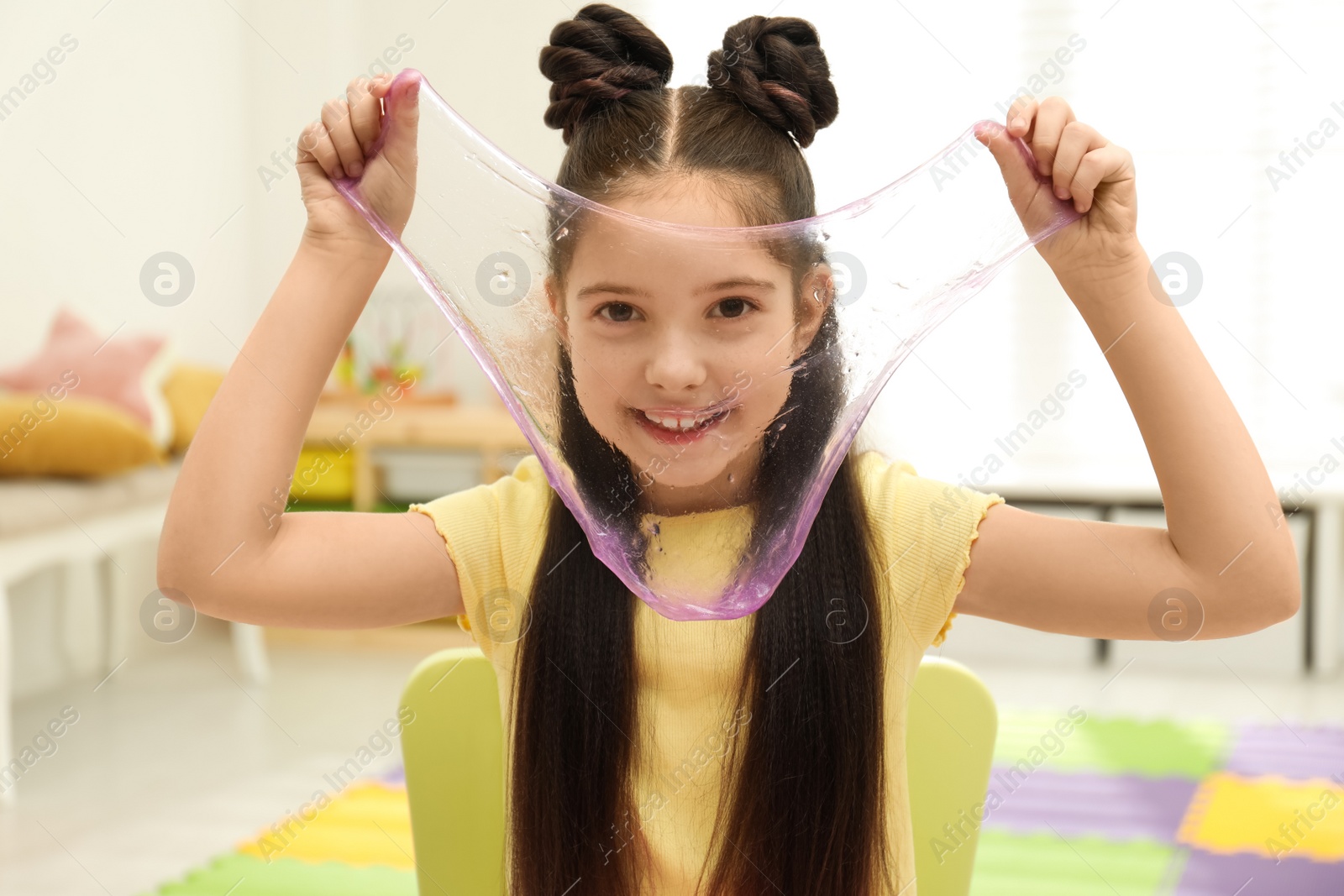 Photo of Little girl playing with slime in room