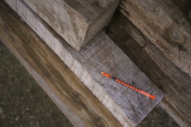 Photo of Disposable syringe with needle on wood outdoors