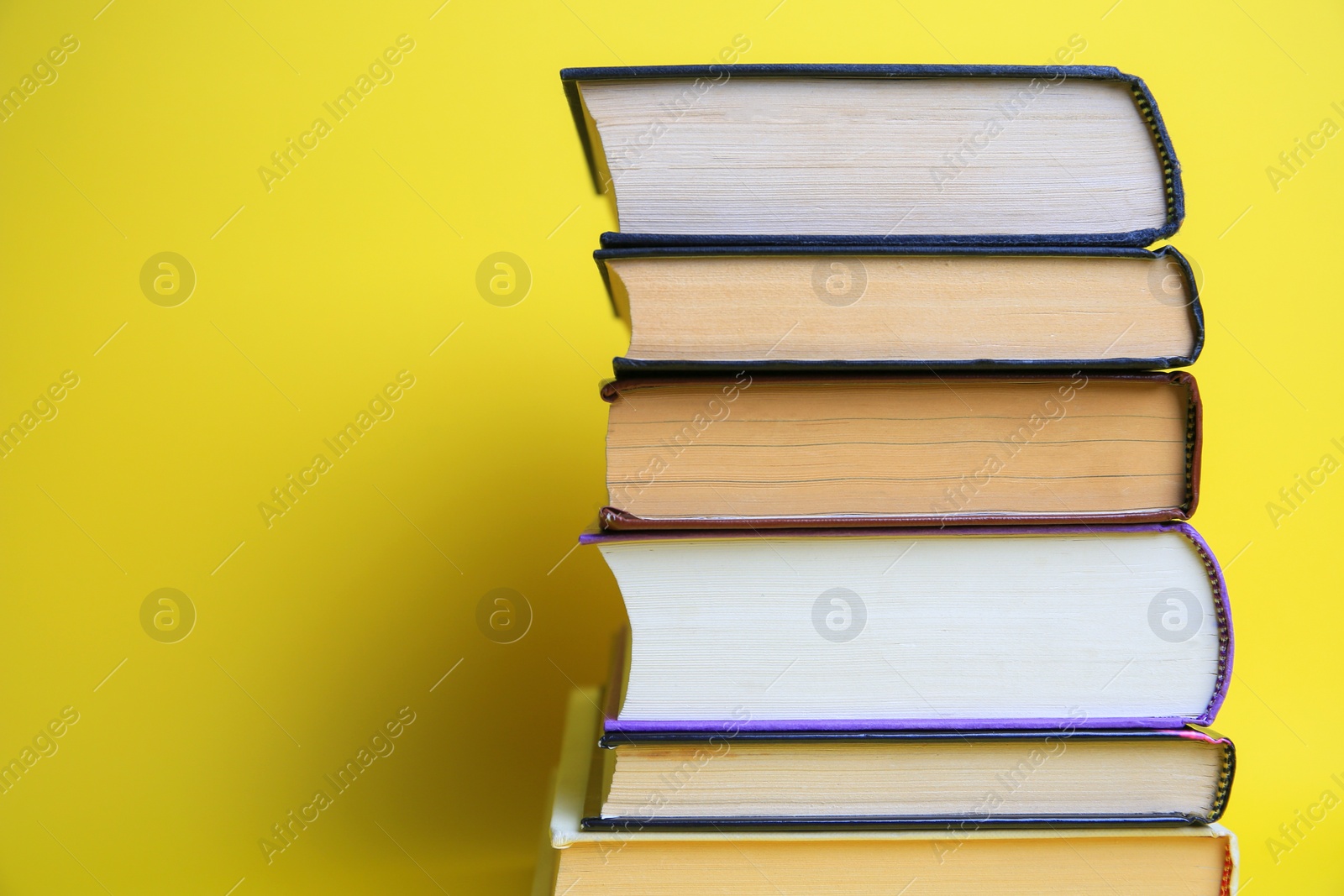 Photo of Collection of hardcover books on yellow background, space for text