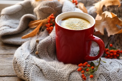 Cup of hot drink, sweater and autumn leaves on wooden table. Cozy atmosphere