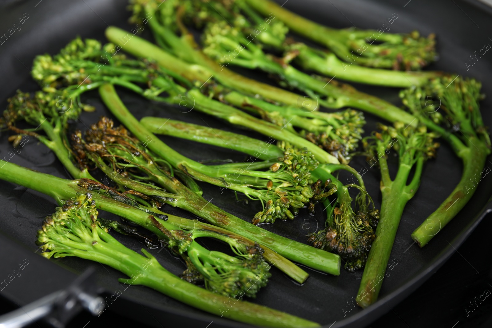 Photo of Grill pan with tasty cooked broccolini, closeup