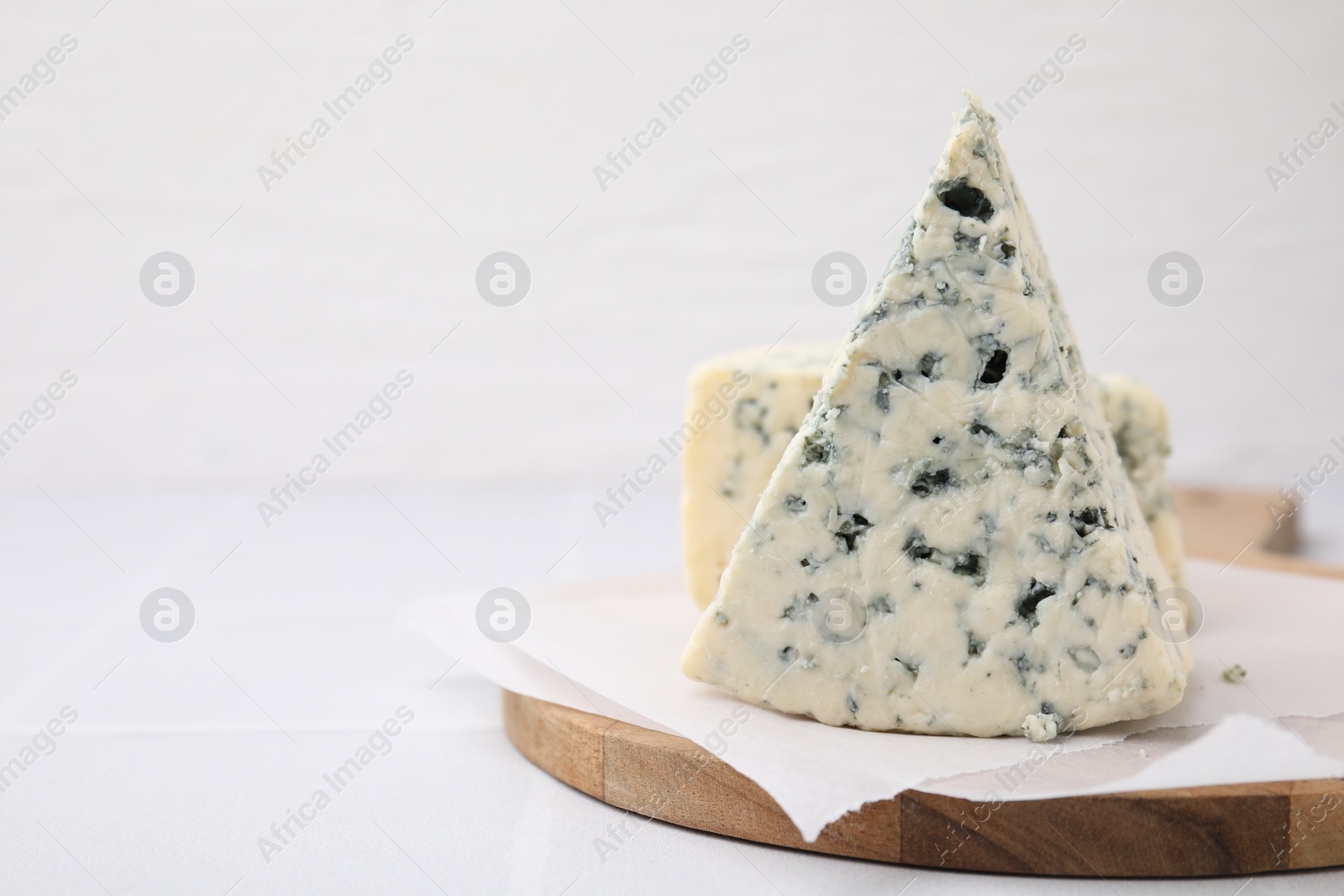Photo of Tasty blue cheese on white table, closeup. Space for text