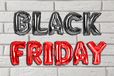 Image of Phrase BLACK FRIDAY made of foil balloon letters against white brick wall