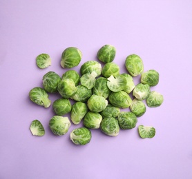 Photo of Fresh Brussels sprouts on violet background, flat lay
