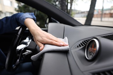 Photo of Woman wiping her modern car with rag, closeup