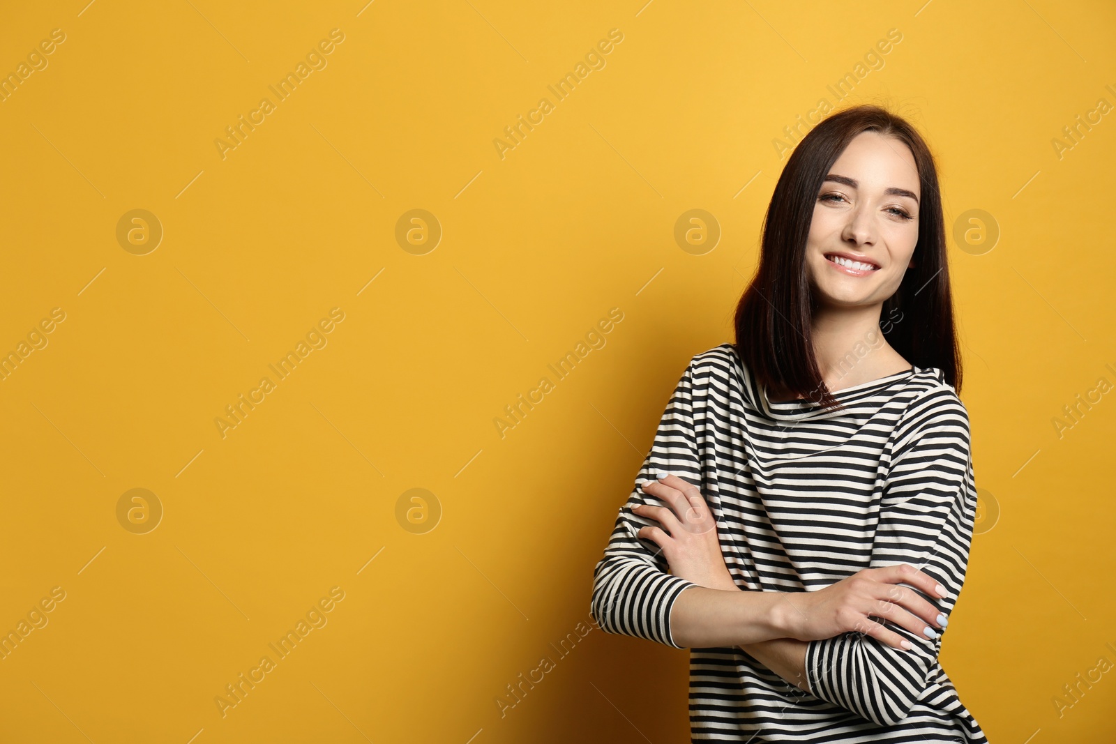 Photo of Portrait of pretty young woman with gorgeous chestnut hair and charming smile on yellow background, space for text