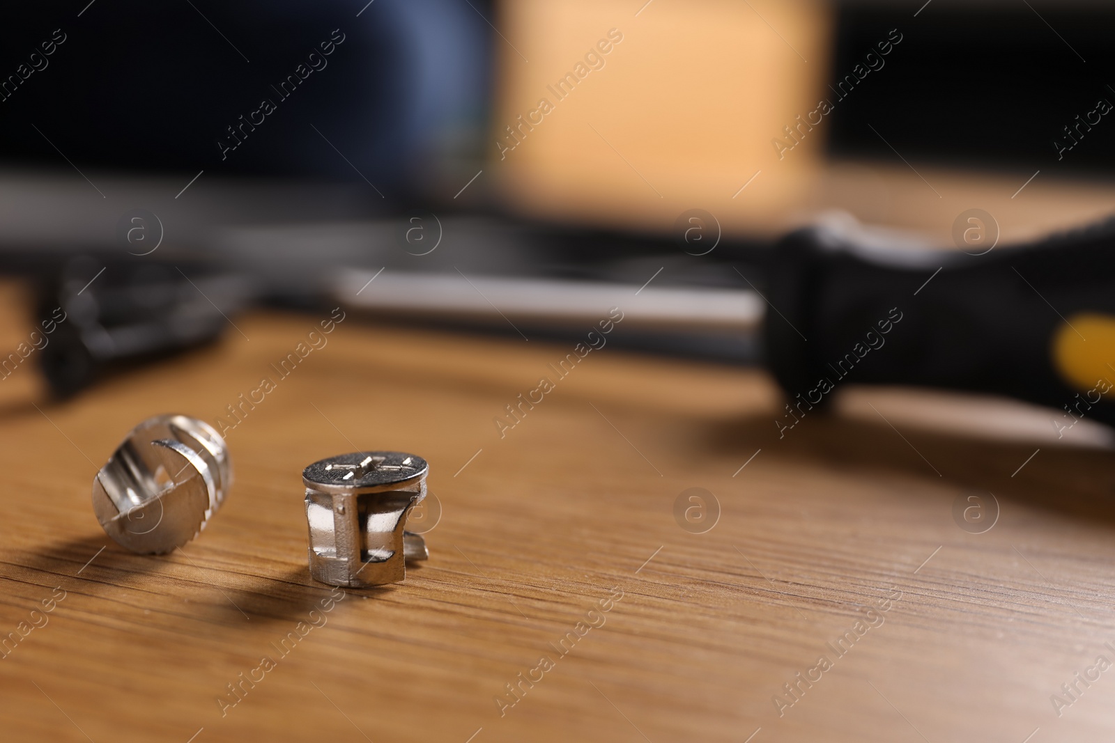 Photo of Locking screws on wooden background, closeup with space for text. Furniture assembly