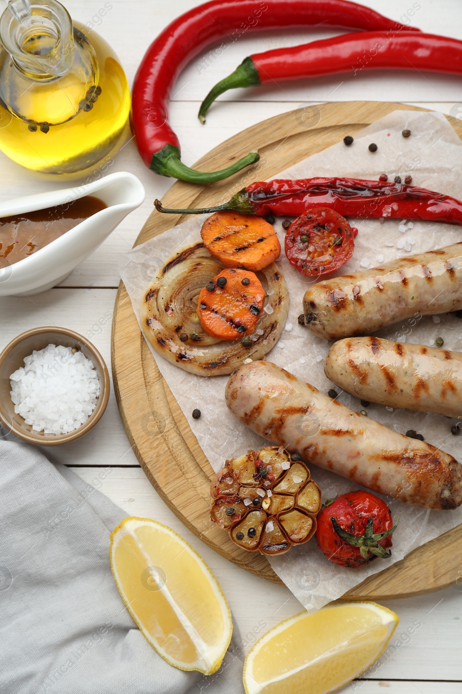 Photo of Tasty grilled sausages served on white wooden table, flat lay