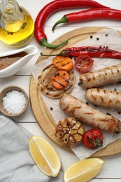 Tasty grilled sausages served on white wooden table, flat lay