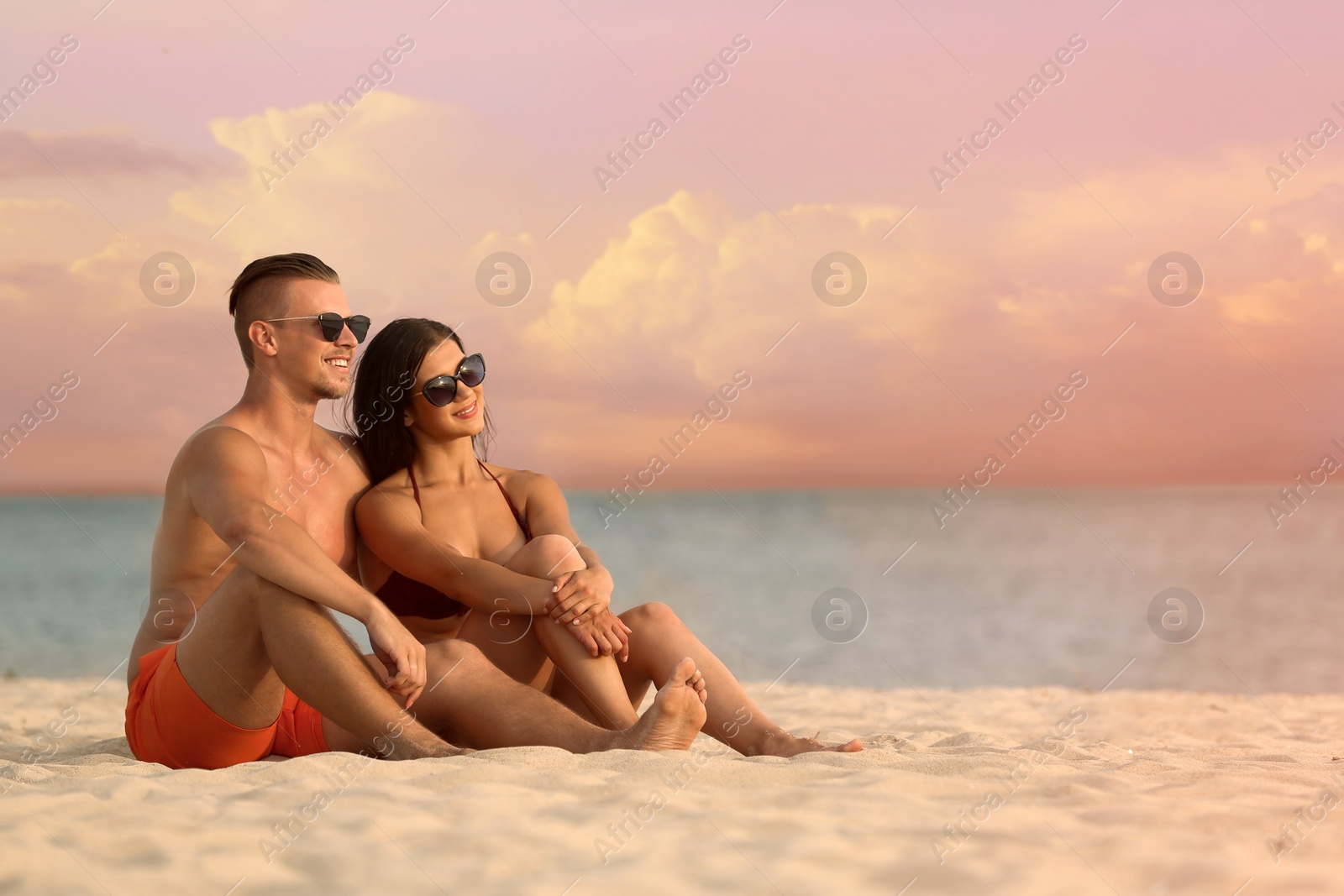 Photo of Young woman in bikini spending time with her boyfriend on beach. Lovely couple