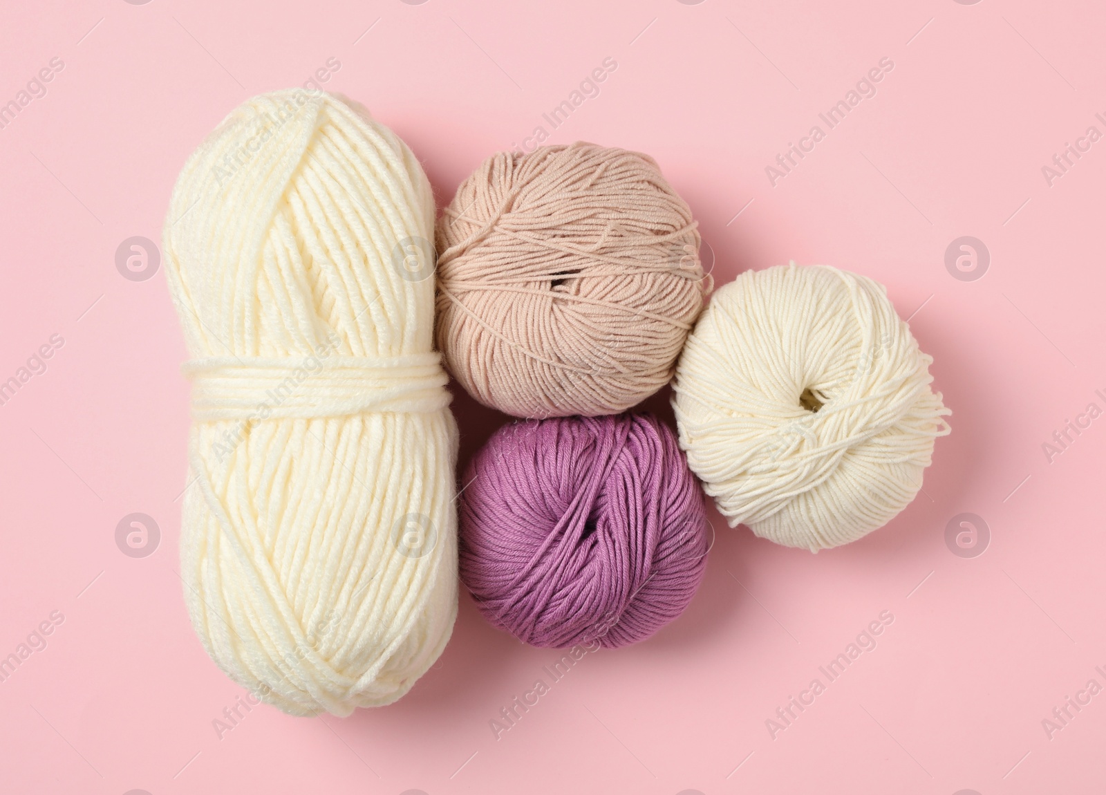 Photo of Soft woolen yarns on pink background, flat lay