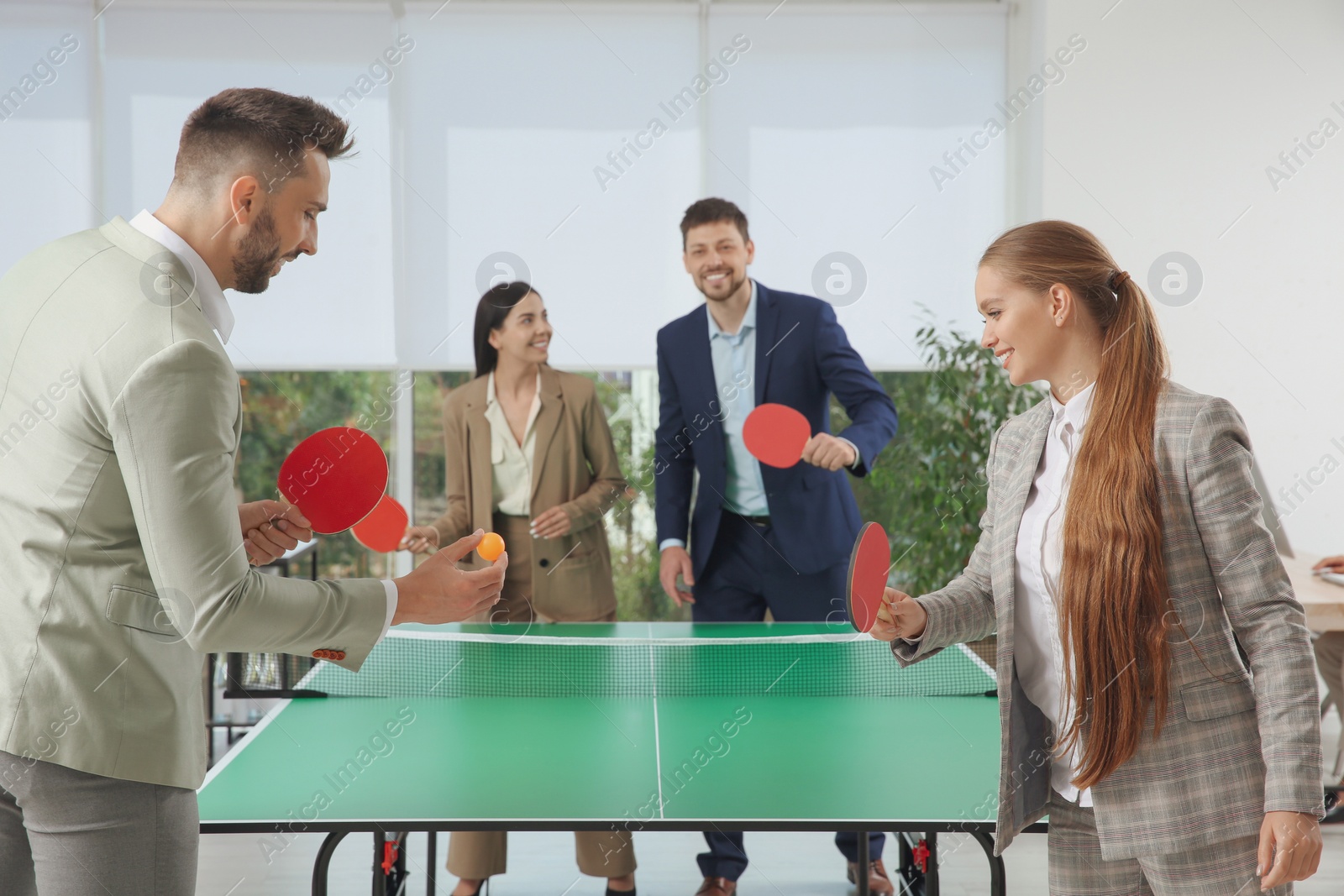 Photo of Business people playing ping pong in office