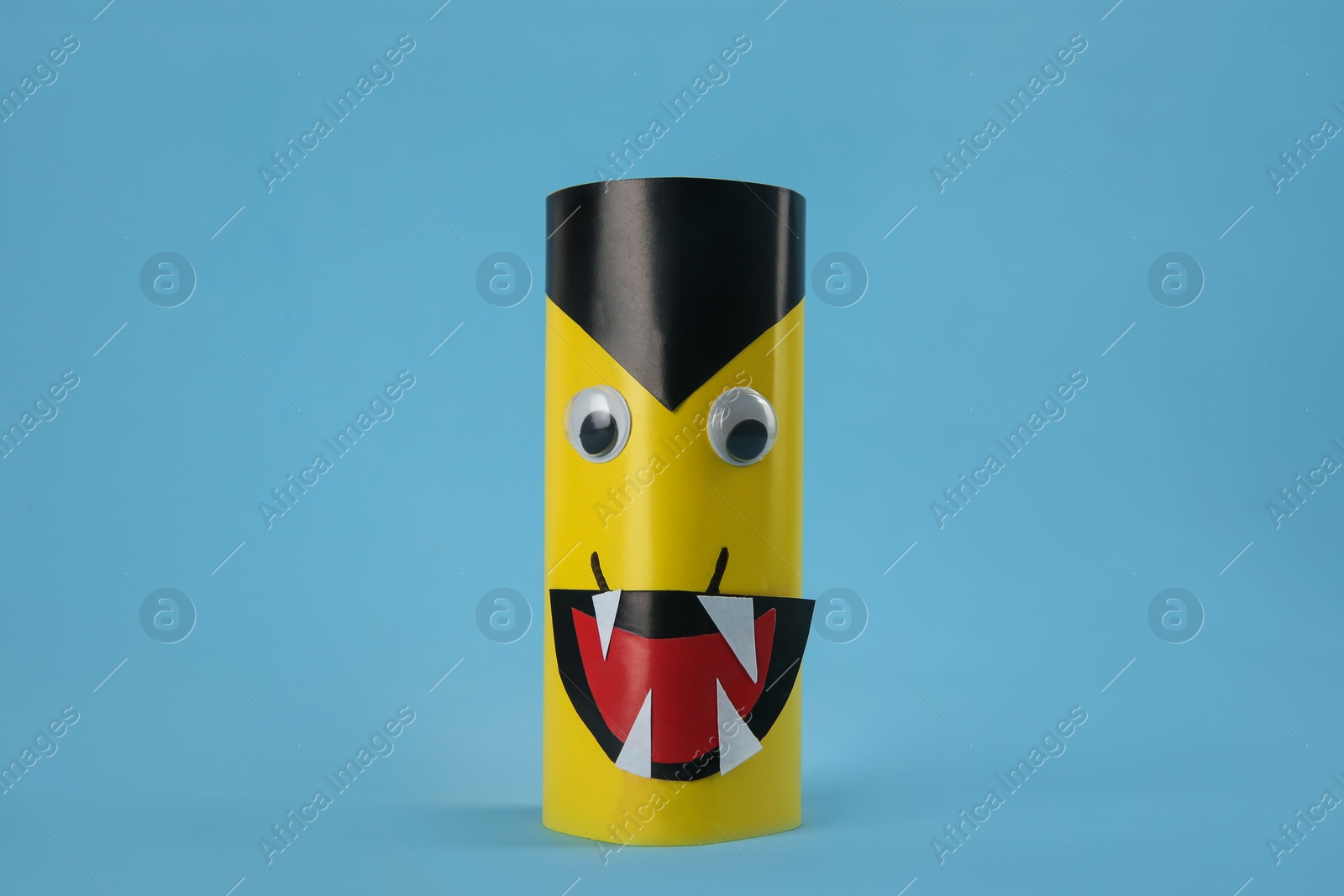 Photo of Funny yellow monster on light blue background. Halloween decoration