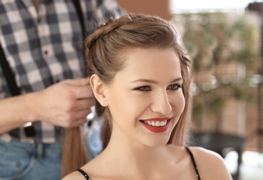 Photo of Professional hairdresser working with client in beauty salon