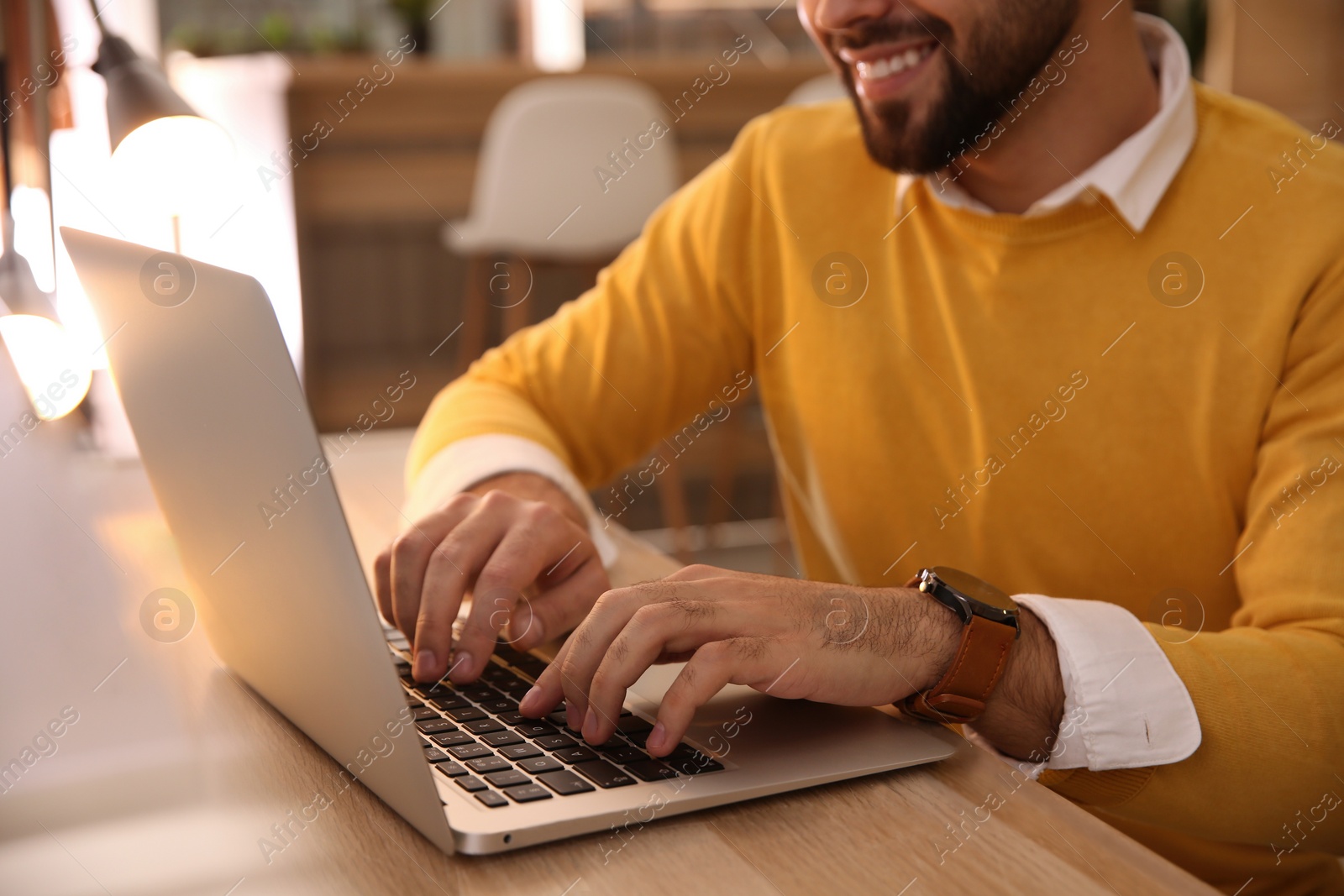 Photo of Man working with laptop at table in cafe, closeup