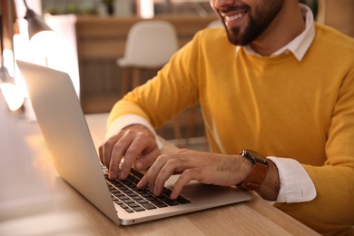 Photo of Man working with laptop at table in cafe, closeup