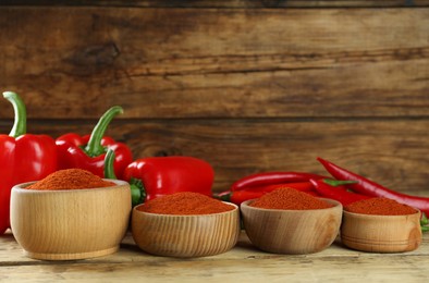 Photo of Bowls of paprika with peppers on wooden table