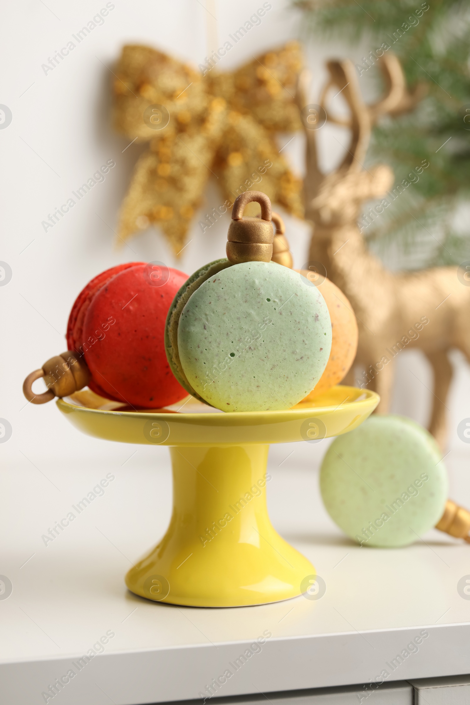 Photo of Stand with beautifully decorated Christmas macarons on white table