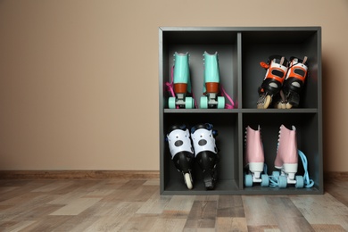 Photo of Pairs of roller skates on shelves near light wall. Space for text