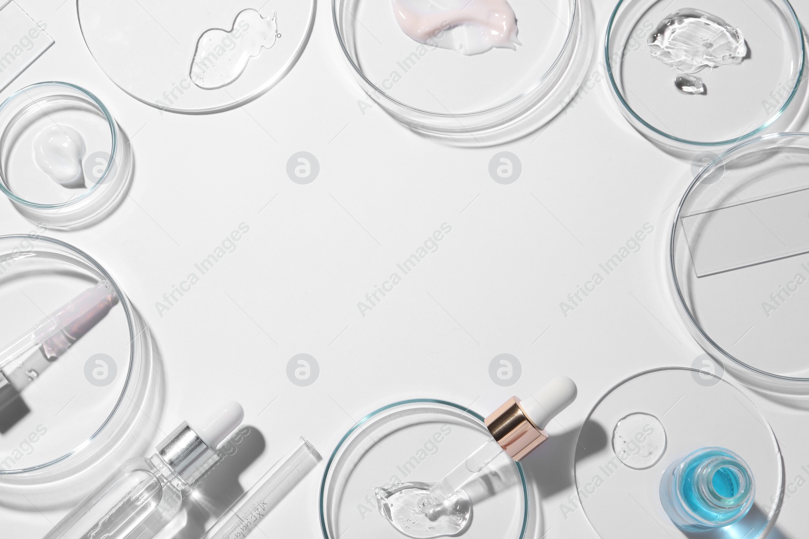 Photo of Frame made of petri dishes, samples of cosmetic serums, bottles and pipettes on white background, flat lay. Space for text