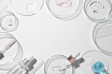 Frame made of petri dishes, samples of cosmetic serums, bottles and pipettes on white background, flat lay. Space for text