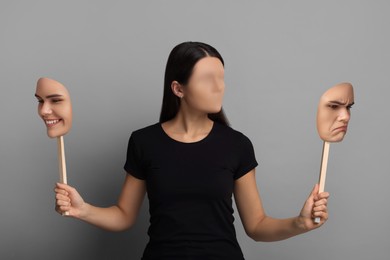 Image of Faceless woman holding her face masks showing different emotions on grey background. Personality crisis.