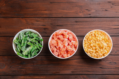 Photo of Different frozen vegetables on wooden table, flat lay
