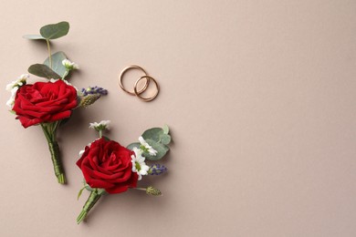 Small stylish boutonnieres and rings on beige background, flat lay. Space for text