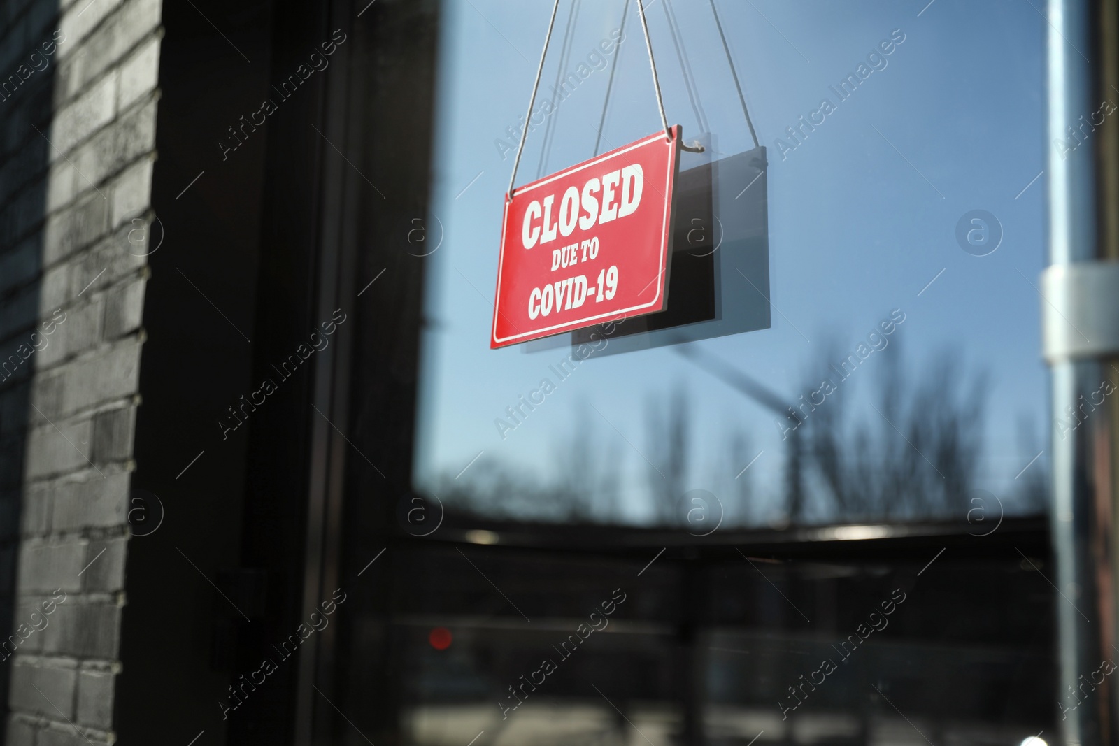 Photo of Red sign with text Closed Due To Covid-19 hanging on glass door. Coronavirus quarantine