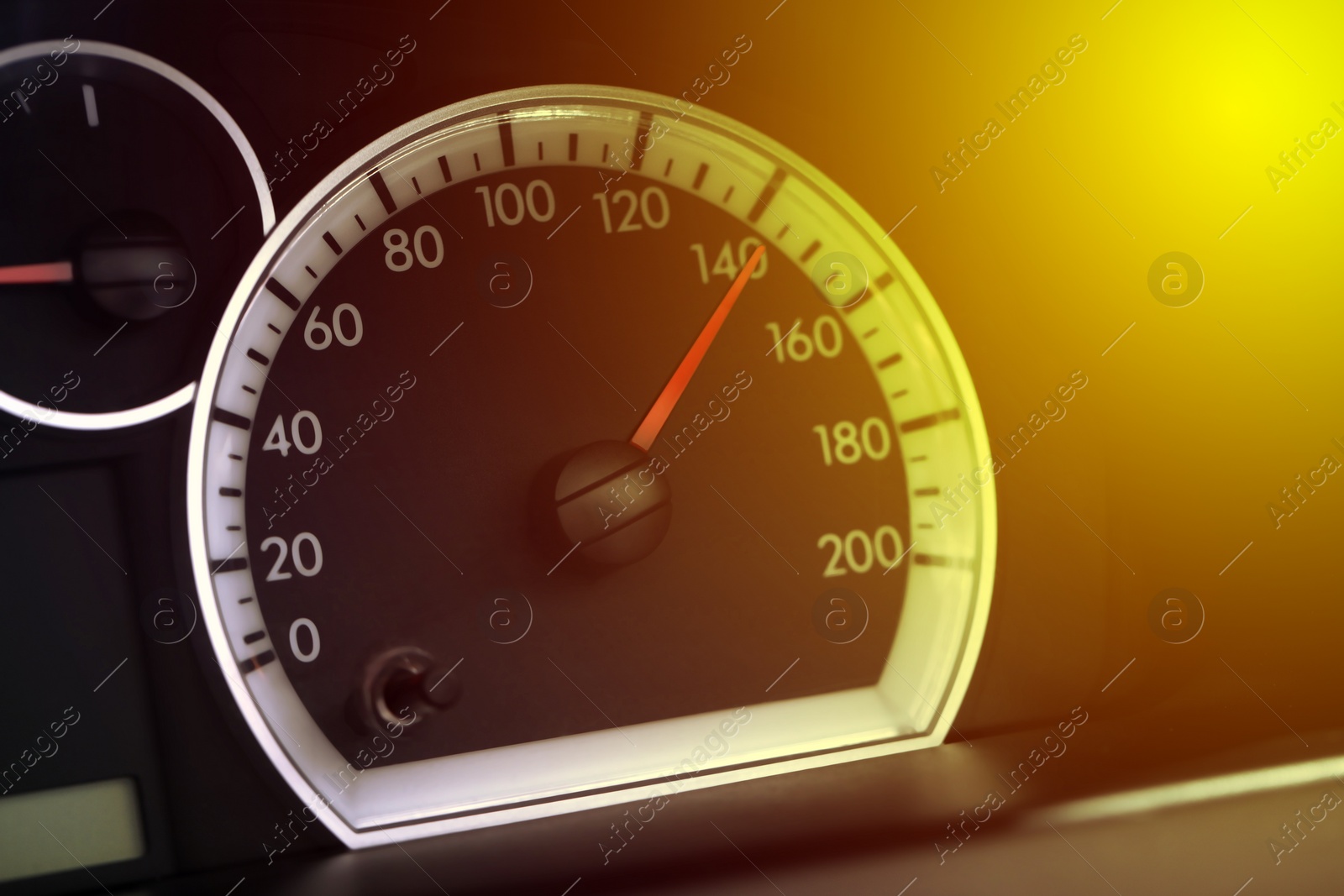 Image of Speedometer on car dashboard under yellow light, closeup