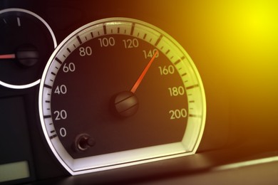 Image of Speedometer on car dashboard under yellow light, closeup