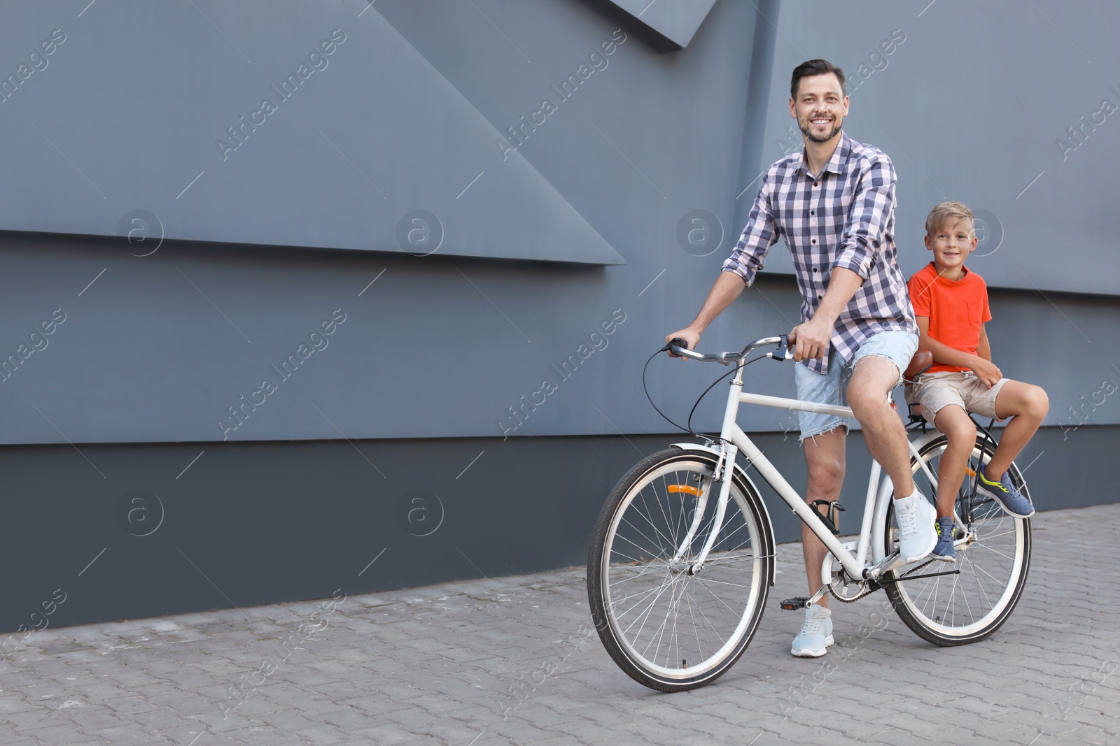 Photo of Father and son riding bicycle on street