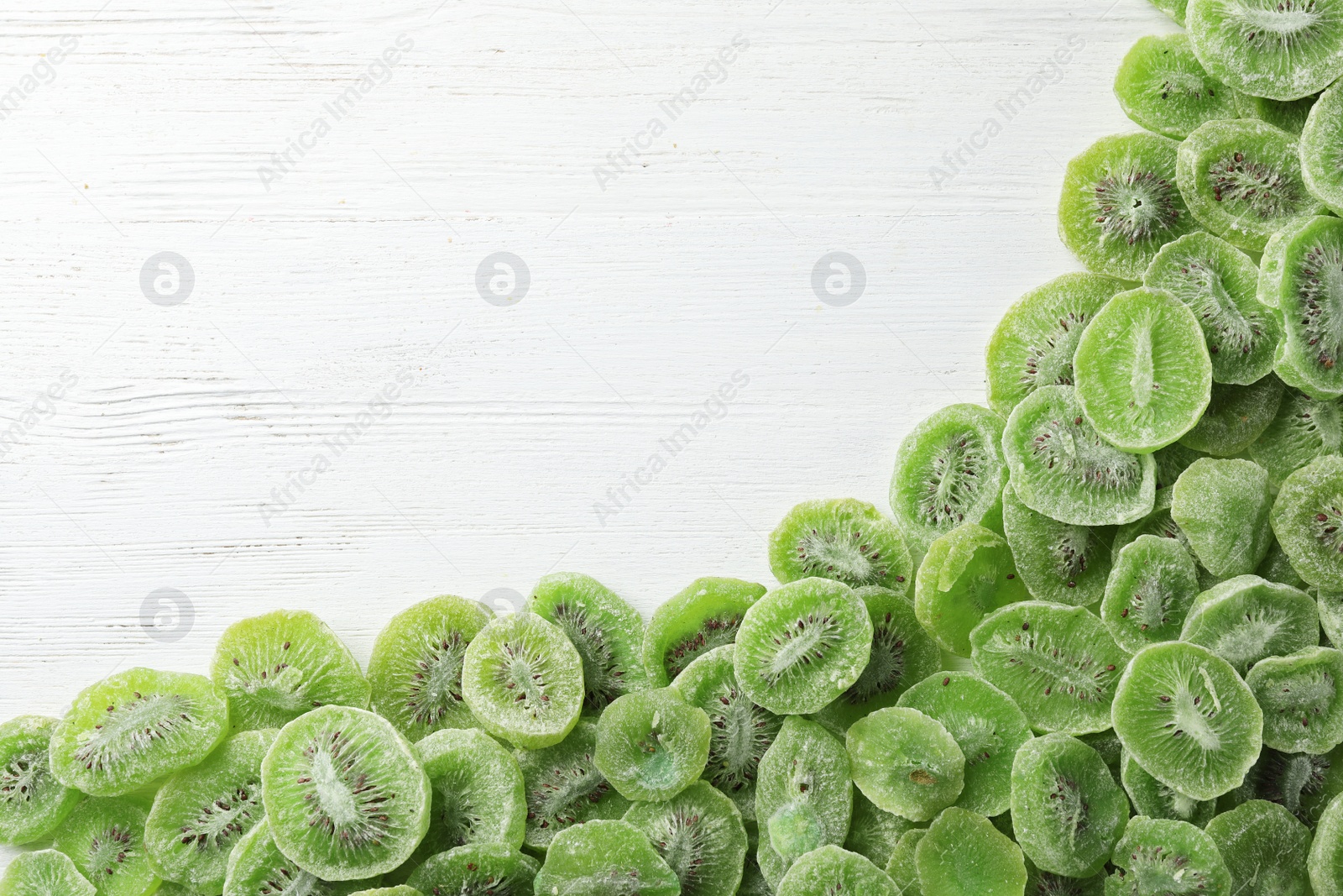 Photo of Frame made of kiwi on wooden background, top view with space for text. Dried fruit as healthy food