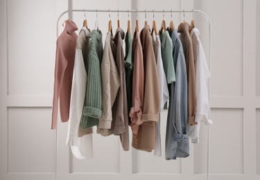 Photo of Rack with stylish women's clothes near light wall
