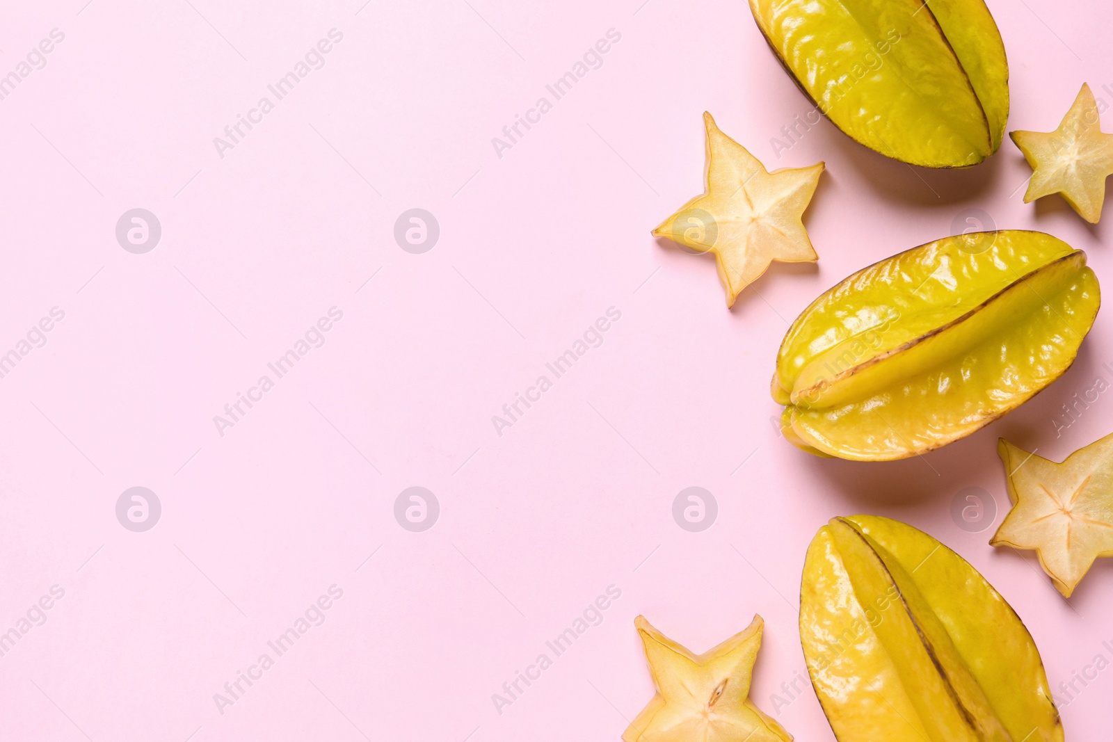 Photo of Delicious carambola fruits on pink background, flat lay. Space for text