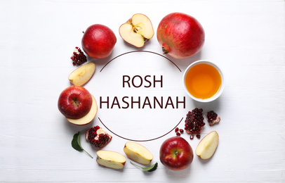 Image of Frame of honey, apples and pomegranates on white wooden table, flat lay. Rosh Hashanah holiday
